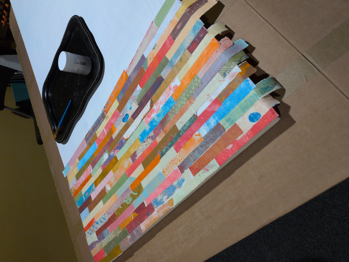 Rows of colorful paper torn into strips and glued in a randomized pattern on a door surface.